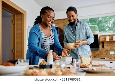 Happy African American woman and her husband setting the dining table for lunch.  - Powered by Shutterstock