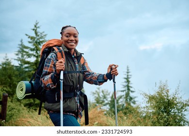 Happy African American woman hiking in the mountains and looking at camera. Copy space. - Powered by Shutterstock