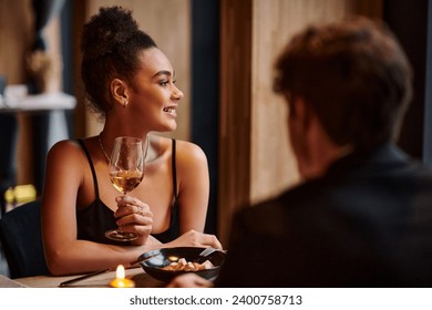 happy african american woman holding wine glass next to boyfriend during date on Valentines day - Powered by Shutterstock