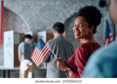 Happy African American woman holding national flag while waiting in a line to vote for the USA elections.  - Powered by Shutterstock