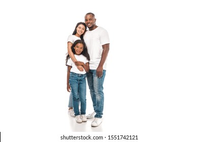 happy african american woman hugging adorable daughter while standing near smiling husband on white background