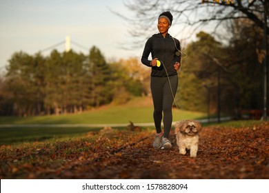 happy African American woman jogging with her dog in nature.  - Powered by Shutterstock