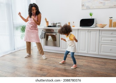 Happy African American Woman And Kid In Aprons Dancing In Kitchen