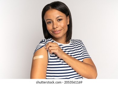 Happy African American Woman Look At Adhesive Plaster On Shoulder After Getting Coronavirus Vaccine. Young Female And Covid-10 Vaccination Injection. Cheerful Vaccinated Girl. Immunization And Health