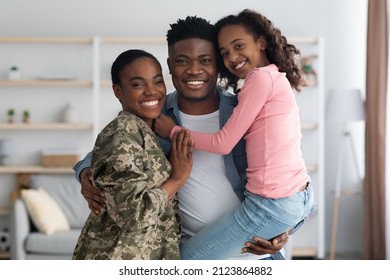 Happy African American Woman In Military Uniform Posing With Her Family At Home, Female Soldier Reunited With Her Husband And Daughter, Embracing All Together And Smiling At Camera, Copy Space