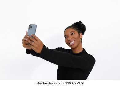 Happy African American Woman With Phone. Female Model In Turtleneck With Curly Hair Taking Selfie In Studio. Portrait, Studio Shot, Emotion Concept