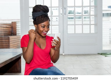 Happy African American Woman Receiving Good News On Phone At Home