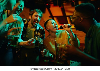 Happy African American woman signing karaoke and having fun with her friends in a bar at night.  - Powered by Shutterstock