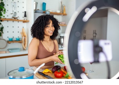 Happy African American Woman Smiling And Demonstrating Ripe Vegetables While Shooting Video For Cooking Vlog In Kitchen At Home