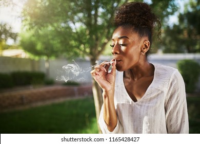 Happy African American Woman Smoking Marijuana Joint In Back Yard