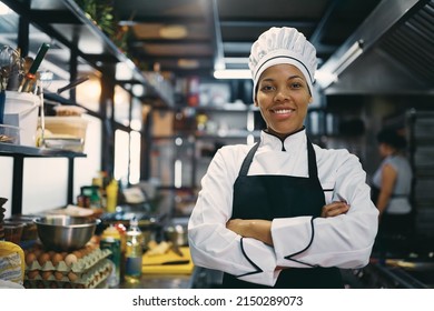 Happy African American woman standing with arms crossed while working as chef in a restaurant and looking at camera. - Powered by Shutterstock
