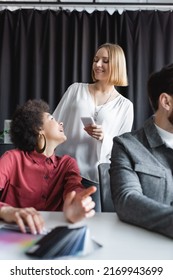 Happy African American Woman Talking To Colleague With Smartphone In Ad Agency