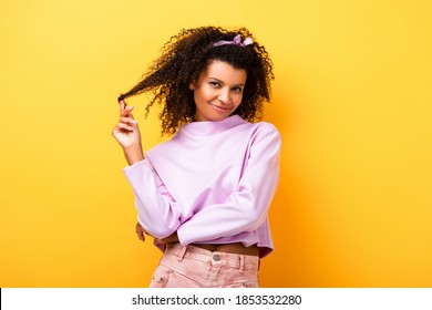 happy african american woman twirling hair on yellow - Powered by Shutterstock