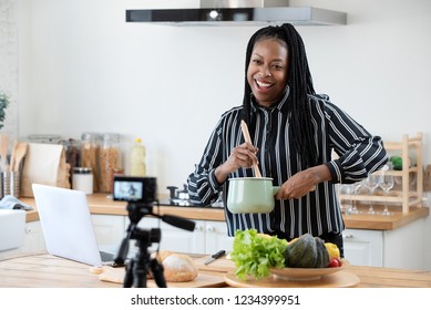 Happy African American Woman Vlogger Broadcasting Live Video Online While Cooking Food In Kitchen At Home