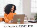 Happy African American woman wearing glasses working on laptop at home