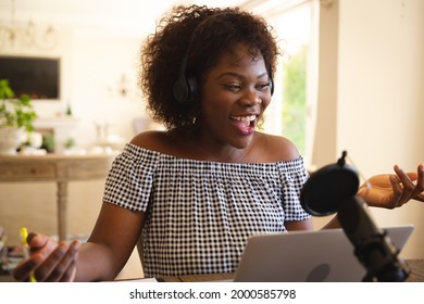 Happy African American Woman Wearing Headphones And Using Microphone, Singing During Podcast. Technology And Communication, Podcasting Online From Home.