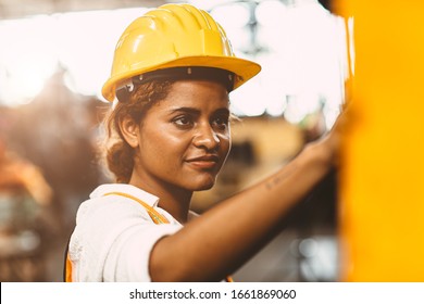 Happy African American Woman Worker With Safety Suit Helmet Enjoy Smiling Working As Labor In Heavy Industry Factory With Steel Machine Operator For Good Welfare.
