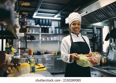 Happy African American woman working as chef at restaurant and preparing food in the kitchen. - Powered by Shutterstock