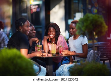 Happy African American Women, friends sitting together at the outdoor restaurant at summer day