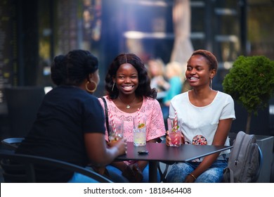 Happy African American Women, Friends Sitting Together At The Outdoor Restaurant At Summer Day