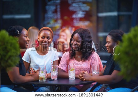 happy african american women, students having fun talking in summer cafe