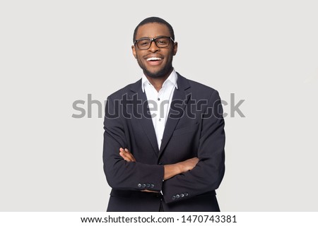 Happy african american young businessman in formal suit wearing eyeglasses portrait. Smiling millennial confident black guy posing for photo, looking at camera, isolated on grey studio background.
