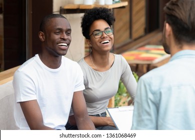 Happy african american young family couple listen to counselor psychologist salesman realtor consult black clients talk to patients customers holding clipboard at meeting, marriage therapy counseling