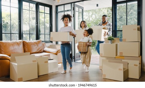 Happy African American Young Family Bought New House. Mom, Dad, And Child Smiling Happy Hold Cardboard Boxes For Move Object Walking Into Big Modern Home. New Real Estate Dwelling, Loan And Mortgage.