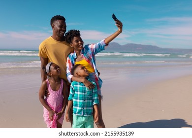 Happy African American Young Woman Taking Selfie With Man, Son, Daughter Over Smartphone At Beach. Nature, Summer, Technology, Unaltered, Childhood, Family, Togetherness, Enjoyment, Holiday.