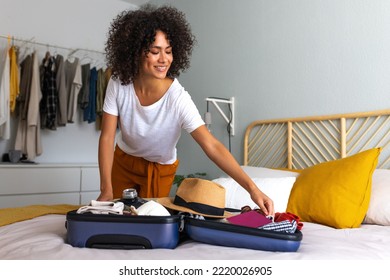 Happy African American young woman packing suitcase at home. Preparing for summer holidays abroad. - Shutterstock ID 2220026905