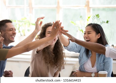 Happy african asian caucasian business people team winners laughing give high five together join hands celebrating connection spirit good relation, successful teamwork victory, unity and teambuilding