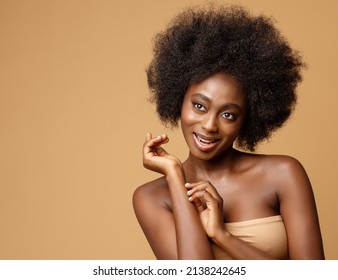 Happy African Beauty Model With Afro Hairstyle. Cheerful Smiling Woman With Dark Skin And Black Coily Hair Over Beige. Face And Body Care