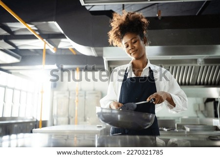 Happy African - black professional chef cooking in kitchen in restaurant.