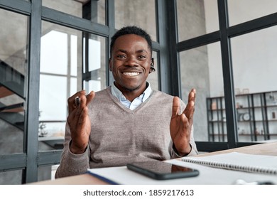 Happy african business man, coach, teacher wearing headset talking to camera conference video calling, giving webinar, online class, distance teaching or working at home office, web cam view. Headshot