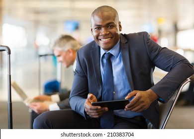 Happy African Business Traveler At Airport Using Tablet Computer While Waiting For Flight