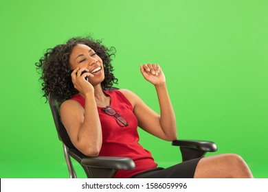 Happy African Businesswoman On The Phone Laughing On Greenscreen. Female Executive Sitting And Chatting On The Phone