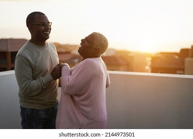 Happy African Couple Dancing Outdoors At Sunset - Main Focus On Man Face