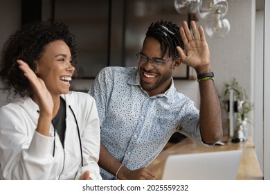 Happy African couple reading on laptop good news gesturing giving high five, feel excited by online bid win, celebrate lottery victory. Achieved new opportunity, loan approval, ecommerce sale concept