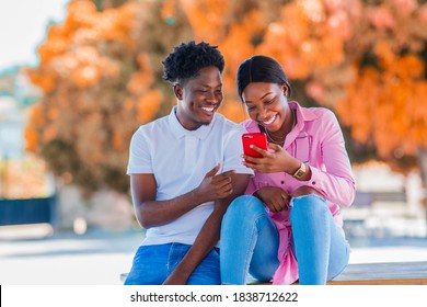 Happy African couple using smartphone outdoors,making video call,online shopping,sharing content on social media - concept Beautiful black friends and phone usage - Powered by Shutterstock