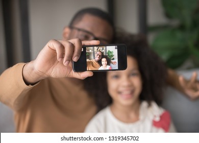 Happy African Dad Taking Selfie With Kid Daughter On Cellphone, Smiling Black Father Holding Phone Making Pic On Modern Smartphone Camera, Daddy And Child Focus Portrait Picture On Mobile Display