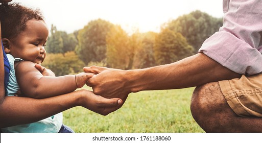 Happy African family having fun together in public park - Black father and mother holding hand with their daughter - people and parent unity concept