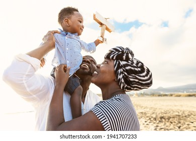 Happy African family having fun on the beach during summer vacation - Parents love and unity concept