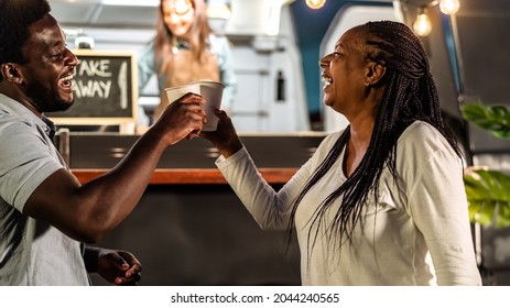 Happy African Family Having Fun Toasting With Beer In A Street Food Truck Market Outdoor