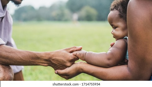Happy african family holdings hands together outdoor during mother day - Mom, father and daughter having tender moments in nature green park - Love and unity concept