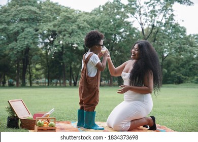 Happy African family Mother and son picnic together at garden green park on weekend. Young mom holding a glass of milk for her kid to drink - Powered by Shutterstock