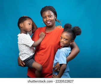 Happy African family from Nigeria consisting of a mother, aunt or guardian, carrying the children, a boy and girl child in her hands - Powered by Shutterstock