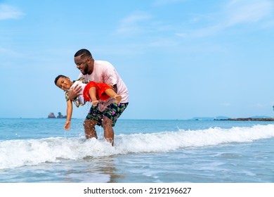 Happy African family on beach holiday vacation. Father playing and carrying little son at tropical beach at summer sunset. Dad with boy kid enjoy and fun outdoor lifestyle activity together at the sea - Powered by Shutterstock