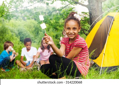 Happy African girl holding stick with marshmallow 