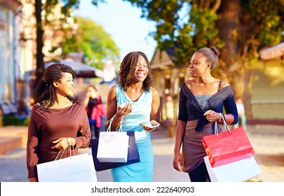 happy african girls walking the street with shopping bags
