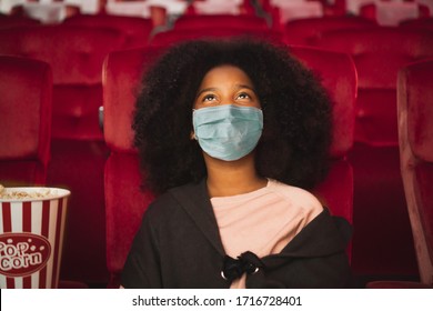 Happy african kid wearing protective face mask and watching movie in theater/theatre cinema protect infection from coronavirus covid-19, social distancing in theater concept - Shutterstock ID 1716728401